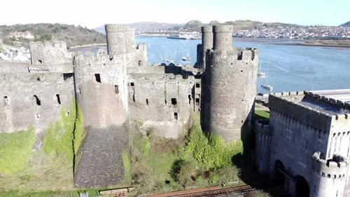 Medieval Conwy castle Welsh market town ruins aerial view historical harbour left orbit shot