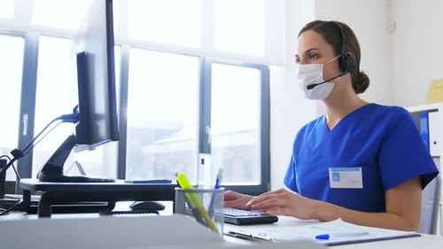 Hispanic female doctor wearing face mask works on computer during coronavirus pandemic