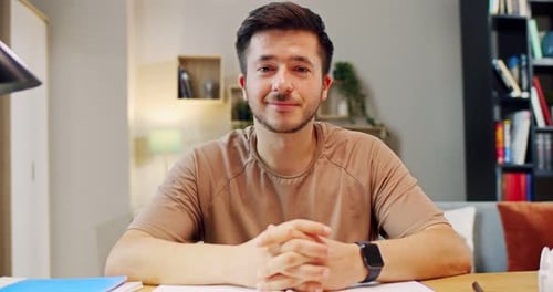 Young Man Smiling At Desk in Home Environment