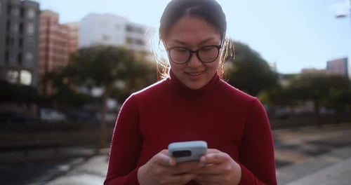 Smiling Woman Uses Smartphone on City Street