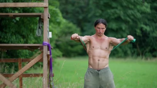 Man Exercising with Resistance Bands in a Green Field