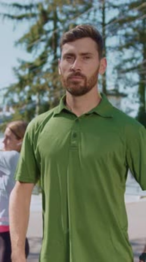 Un homme confiant portant un polo vert vif debout à l'extérieur au soleil