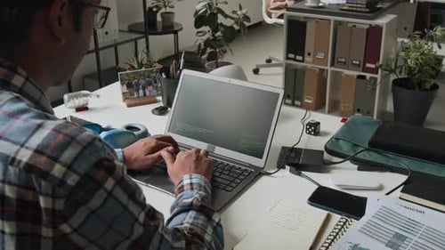 Male Software Engineer Coding on Laptop in Office