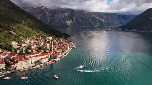 Vue aérienne par drone de la ville à flanc de colline de Perast, mettant en évidence le haut clocher de l'église et le toit rouge dense
