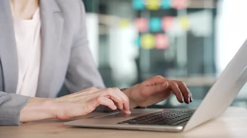 Close up of female hands typing on laptop keyboard in modern office. A businesswoman works