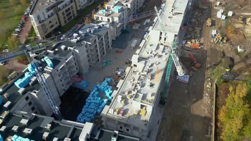 Survol aérien d'un site de développement de nouvelles constructions avec des grues à haute tour qui construisent des biens immobiliers.