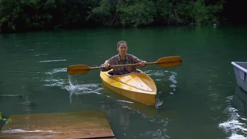 Young Woman Paddling Kayak on Calm Lake