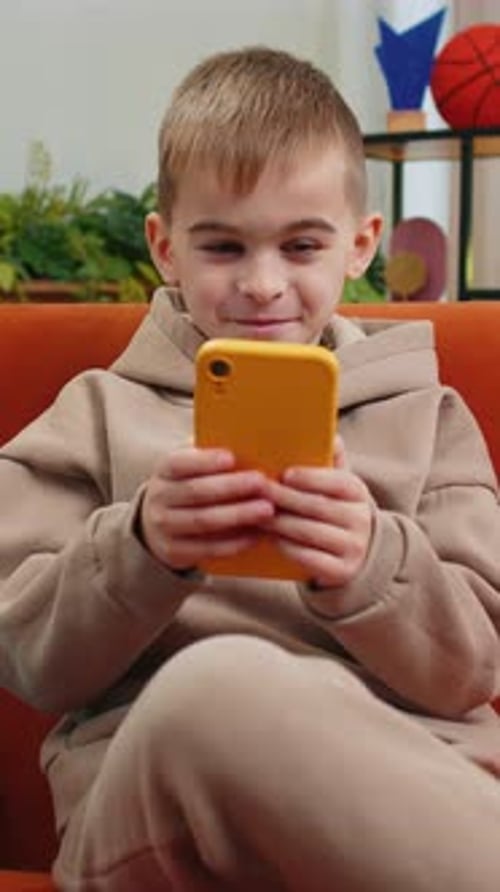 Young Boy Watching Content on Phone While Relaxing Indoors