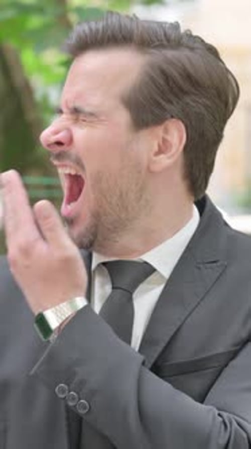 Man in Suit Yawns Outdoors During the Daytime