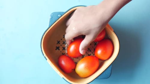 Cleaning Fresh Tomato with a Water in a Plastic Bowl
