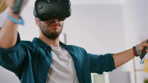 Man using virtual reality headset and controllers indoors