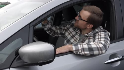Man customer sitting in car salon and touching the steering wheel, choosing auto and wanting to buy