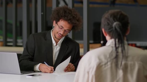Young Man Signs Business Documents at Office Desk