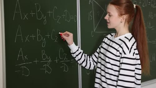 Student Writing Equations on Chalkboard in Classroom