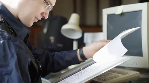 Un oficial de policía repasa el papeleo en una computadora HD