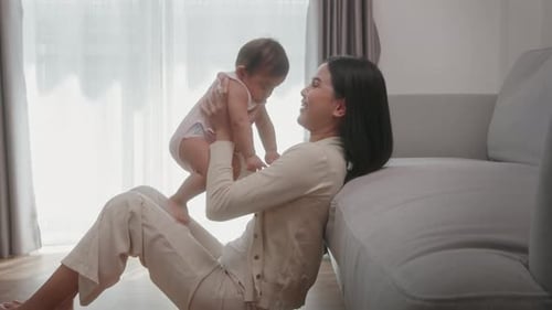 Mother Holds Baby Up in the Air at Home
