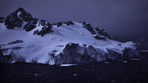 Vertical Ice Constructs Overshadow Rugged Shoreline Beneath Agitated Sea Surface