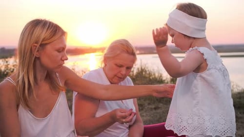 A Family of Only Female Members Sitting on a Picnic on a Hill During Sunset and Eating Berry Pie and