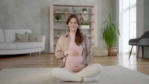 Pregnant Woman Smiling and Sitting in Lotus Position
