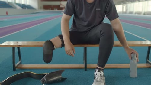 Athlete with Prosthetic Leg Resting at Track