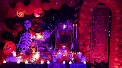 Espeluznante altar del Día de Muertos con decoraciones, velas y luz morada.