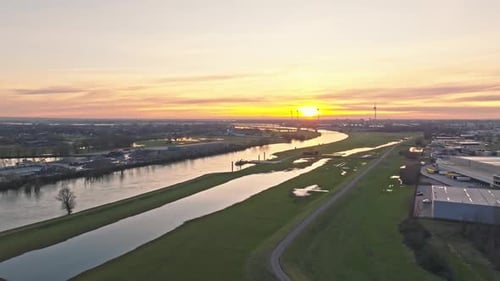 Aerial sunset drone shot passing over industrial area with impressive windturbines and bridge on the
