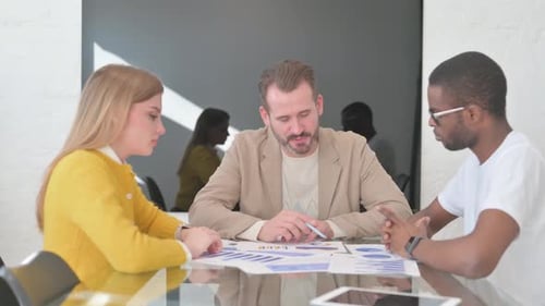 Colleagues Analyzing Business Charts in Workplace Meeting