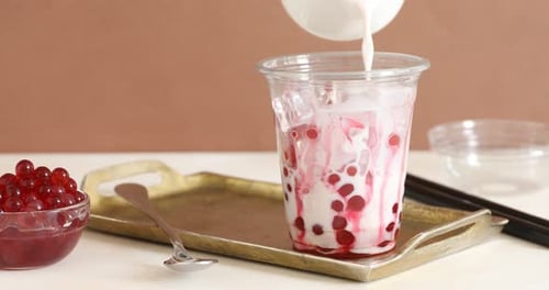 Woman making tasty milk bubble tea at white table, closeup