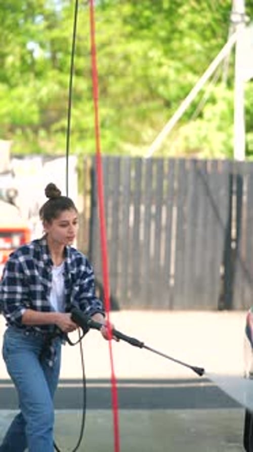 Woman Washing a Car with a Power Washer
