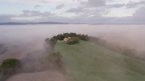 Aerial view of misty villa and cypress trees in countryside, Italy.