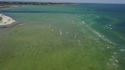 Aerial of Many Kiteboarders with Colorful Kites Flying Over the Blue Sea Lagoon Ride on Kiteboards
