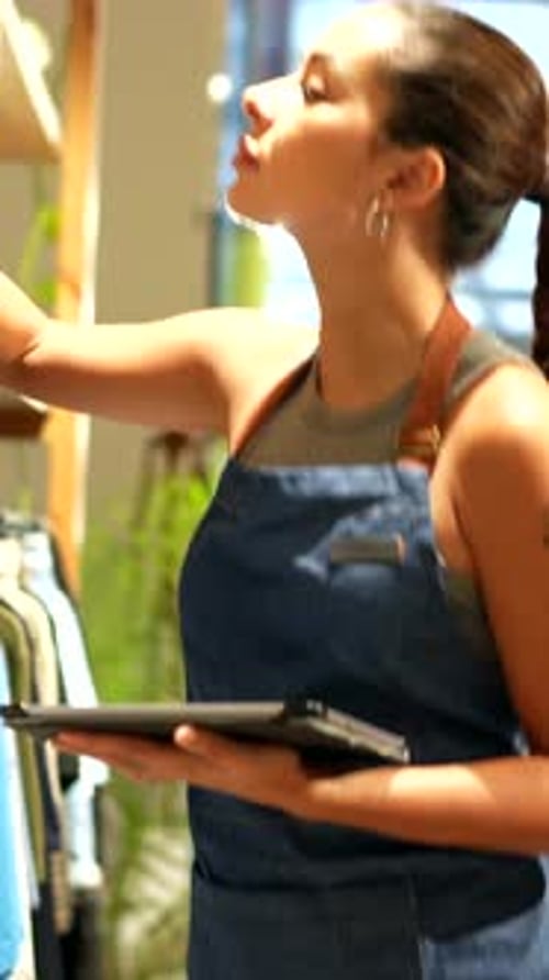 Saleswoman Using Digital Tablet Taking Inventory in Clothing Store