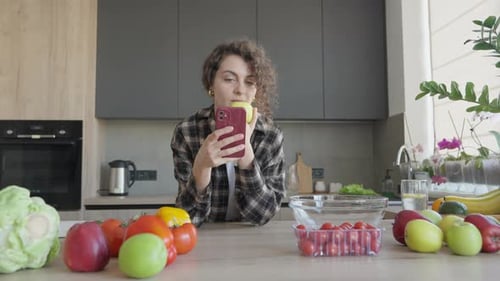 Woman With Apple and Phone in Modern Kitchen