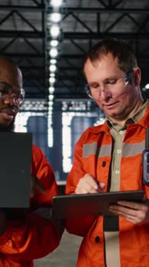 Vertical Video Colleagues Use Laptop and Tablet to Guide Personnel During Fabrication