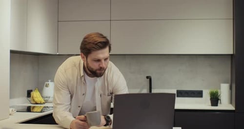 Man Working on Laptop in Modern Kitchen