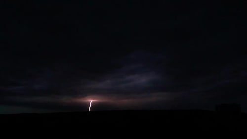 Flashes of lightning in the night sky among thunderclouds.
