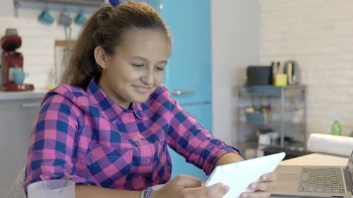 Teen Girl Studies with Tablet in Bright Kitchen