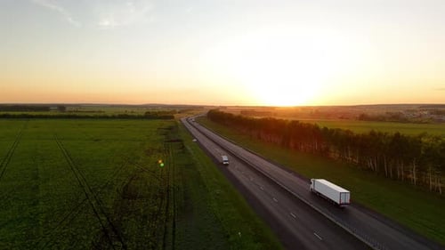 Heavy Truck Driving on an Asphalt Road Along Green Fields
