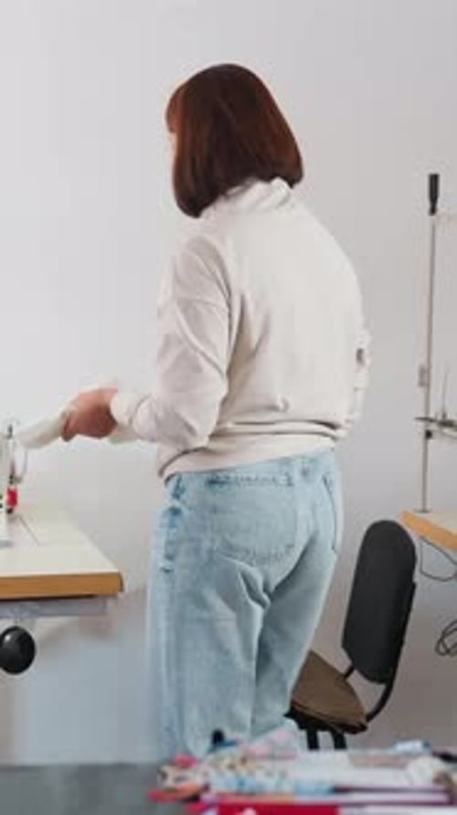 Woman Examines Fabric Seamstress Reviews Garment Details Female Worker Inspects Clothing in Studio