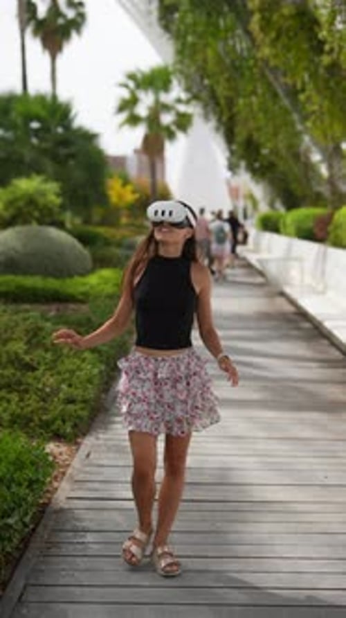 A Woman Walks in a Garden Wearing a Headset Blending the Outdoor Ambiance with Modern Technology