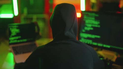 Hooded Figure Coding on Computers at Night