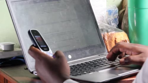 Hinter dem Laptop, Hände, die am Telefon tippen
