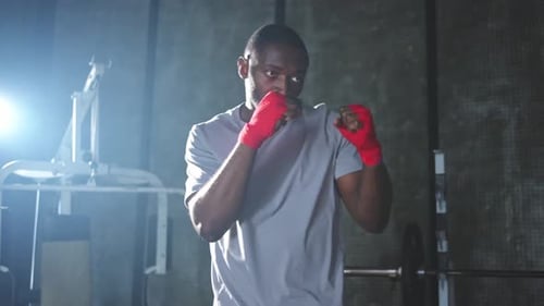 Fitness Workout in Gym African Man Fighter Preparing for Fight Punching with Red Boxing Wraps Sports