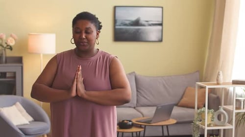 Mujer negra con cuerpo positivo practicando yoga en casa