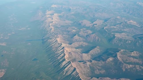 Aerial drone view of rugged desert mountains and shadowed ridges at golden hour