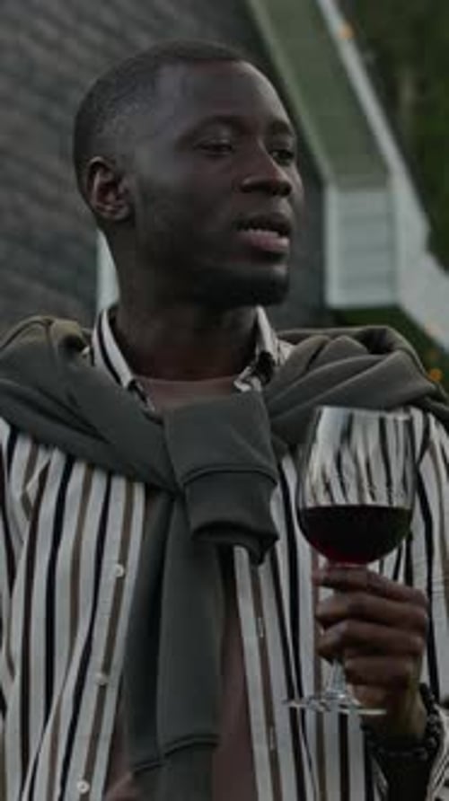 Vertical of Young Black Man with Glass of Red Wine on Patio