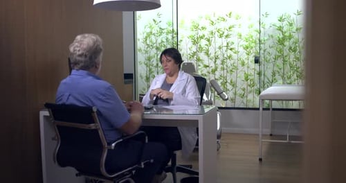 Mature Man Consults with Woman Doctor in Office