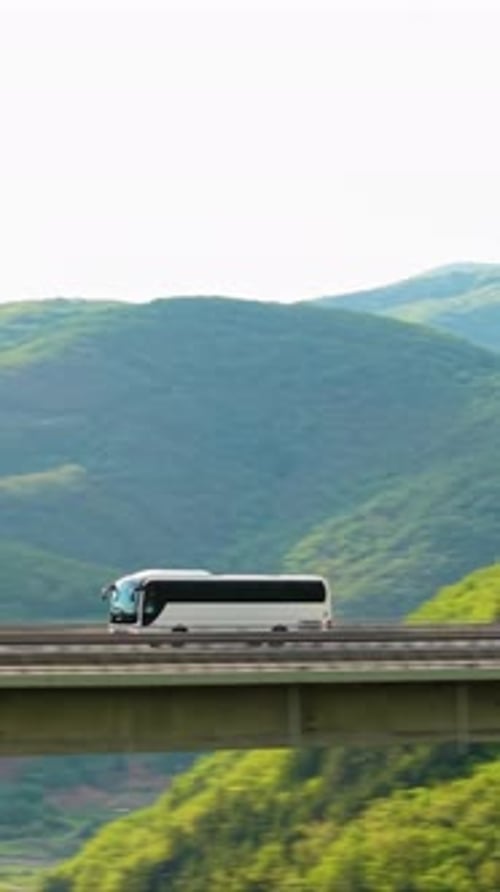Passenger Bus Driving Along Mountain Road Surrounded By Lush Green Hills Aerial View