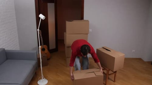 Young Man Moving Boxes in New Apartment