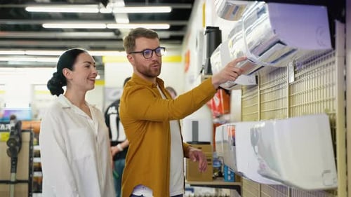Young Couple Choosing Air Conditioner in Appliances Store